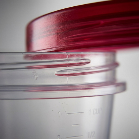 Extreme close-up macro view of the interlocking threads of the Twist & Seal lid on the clear body, in ruby and transparent plastic, demonstrating the secure, airtight closure.