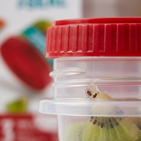 A macro view focusing on the deep plastic threads and ridged grip of the red Twist & Seal lid, showing a tight seal on the clear base against fresh kiwi pieces.